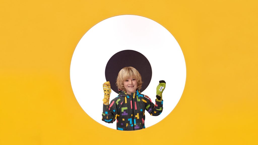 Zdjęcie przedstawia chłopca w rozpinanej czarnej bluzie w kolorowe geometryczne wzory