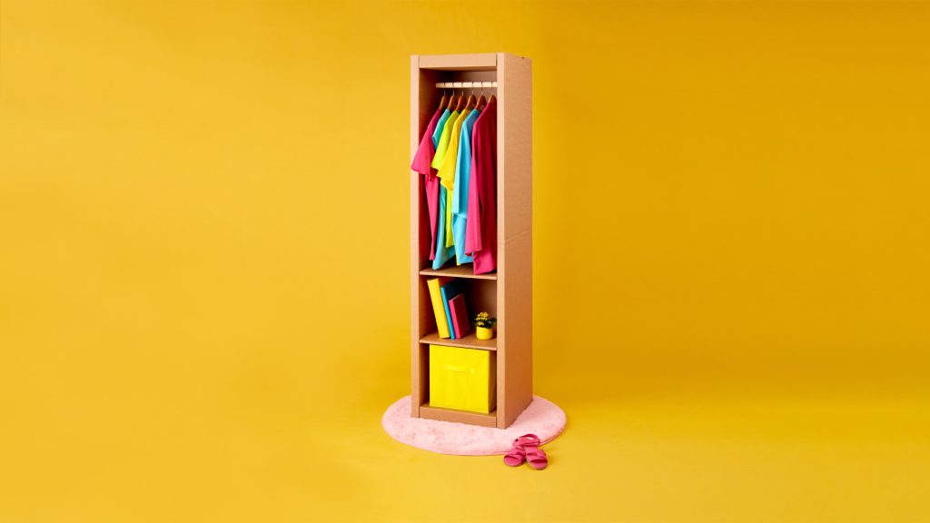 podłużna, wysoka szafa z kartonu, z miejscem na wieszaki, oraz 2 półkami