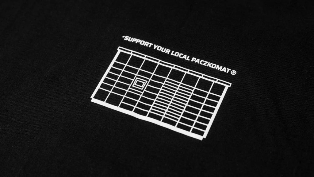 Biała naszywka na czarnej bluzie z urządzeniem Paczkomat oraz napisem Support your local Paczkomat