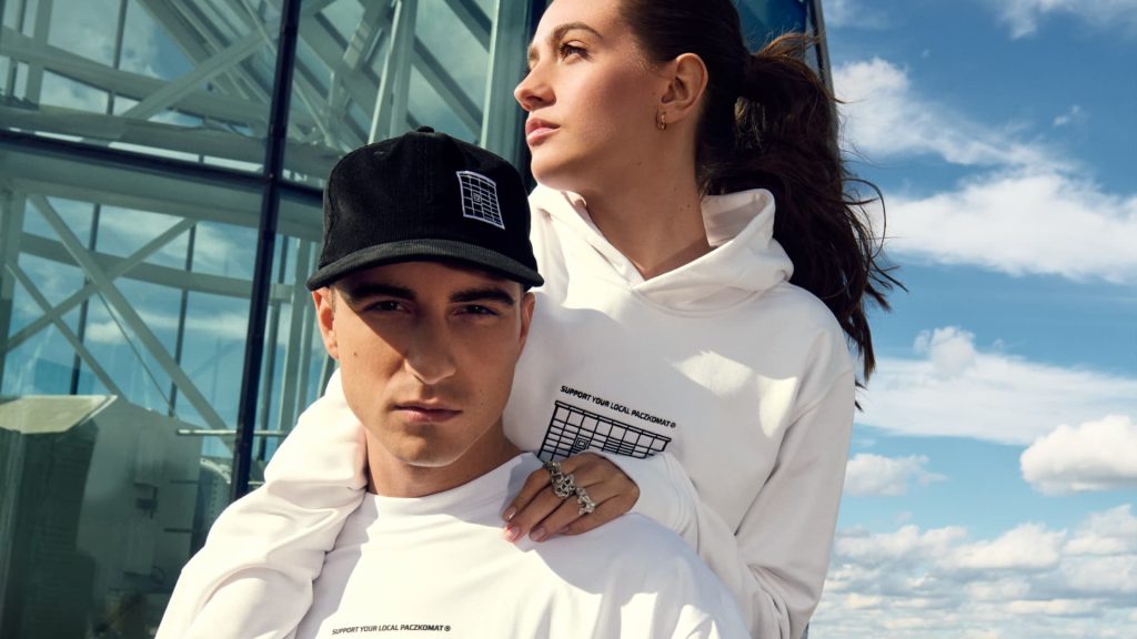 Czarna czapka sztruksowa z daszkiem, onesize z klamrą do regulowania wielkości, z hatem maszyny Paczkomat z przodu, w środku czapki wszywka z napisem Support your local Paczkomat