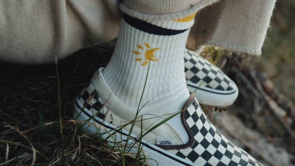Skarpetki z żółtym nadrukiem słońca i trampki Vans w szachownicę.