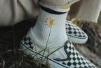 Skarpetki z żółtym nadrukiem słońca i trampki Vans w szachownicę.